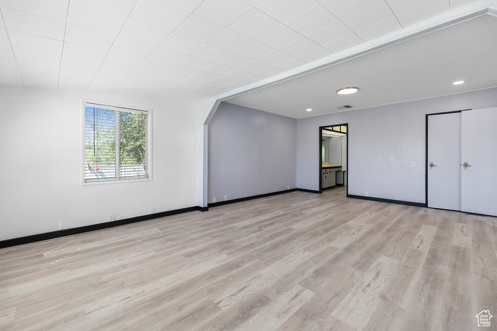 Unfurnished bedroom featuring light wood-style flooring, baseboards, arched walkways, and recessed lighting