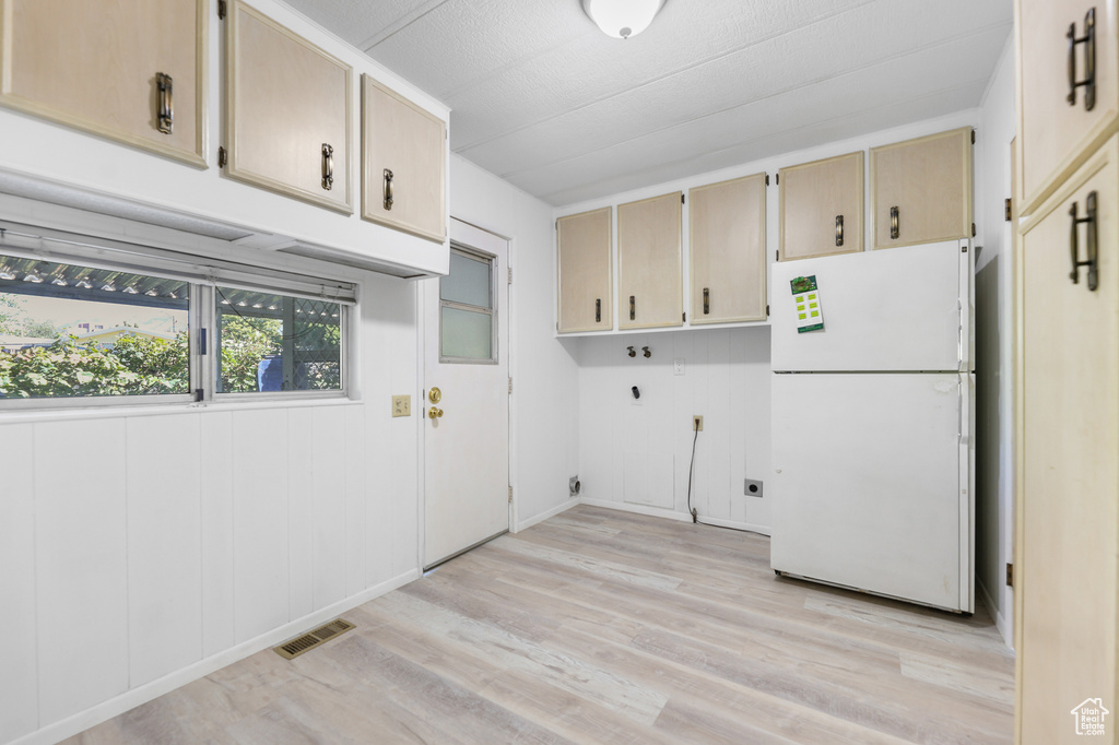 Washroom featuring electric dryer hookup, cabinet space, light wood finished floors, and hookup for a washing machine