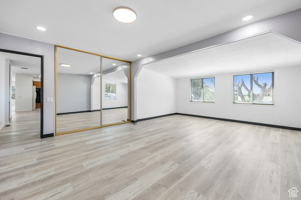 Unfurnished room with wood finished floors, plenty of natural light, baseboards, and recessed lighting