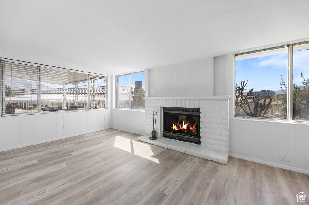 Unfurnished living room featuring a fireplace, wood finished floors, baseboards, and vaulted ceiling