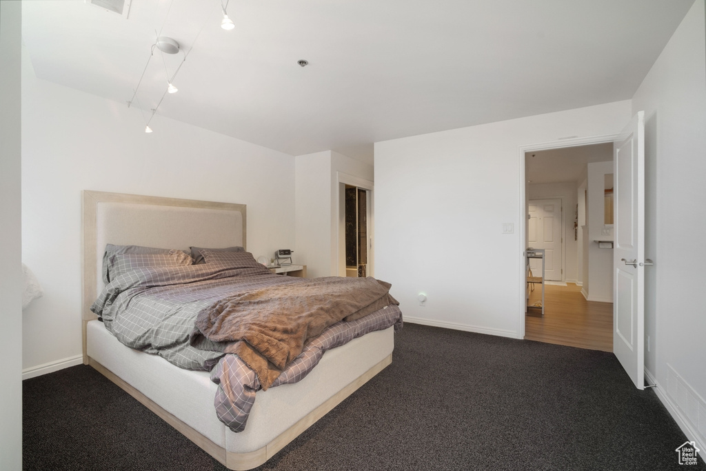 Bedroom with dark colored carpet and baseboards