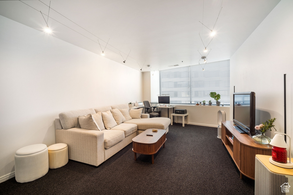 Living area featuring a desk, dark carpet, baseboards, and rail lighting