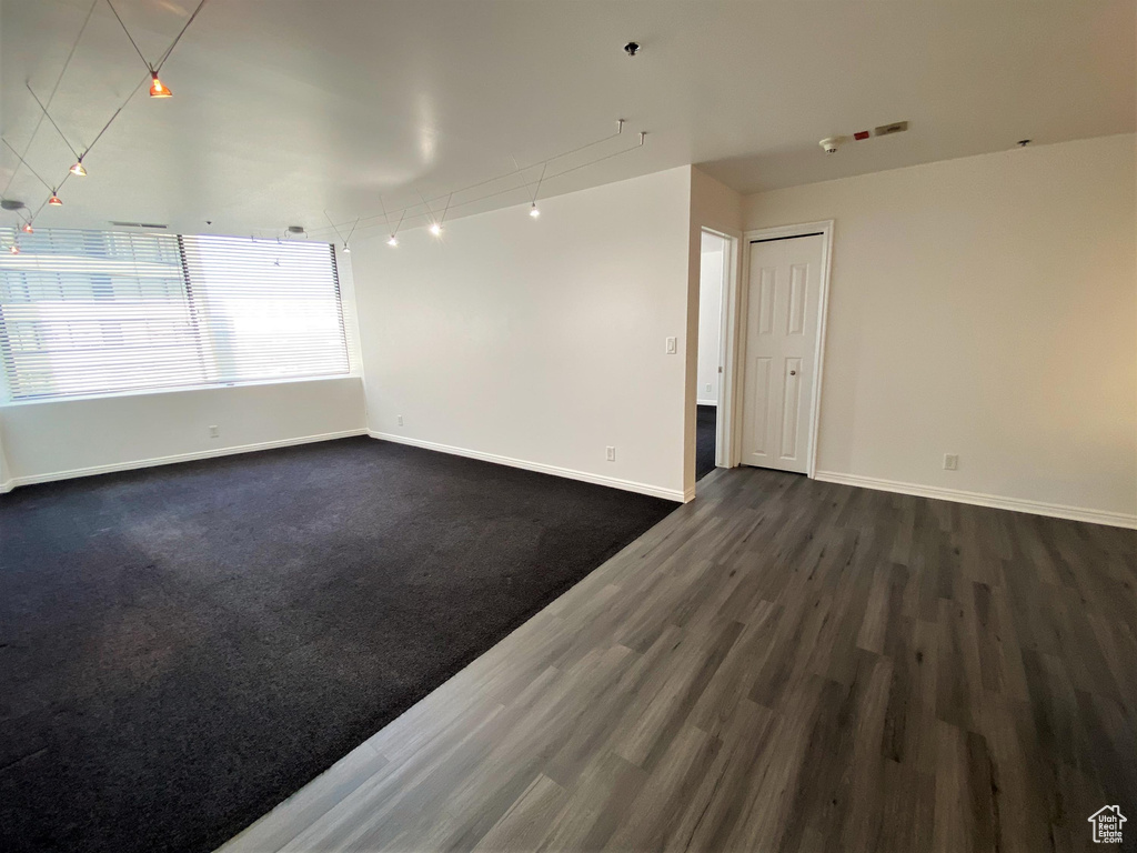 Spare room featuring baseboards and dark wood-style flooring