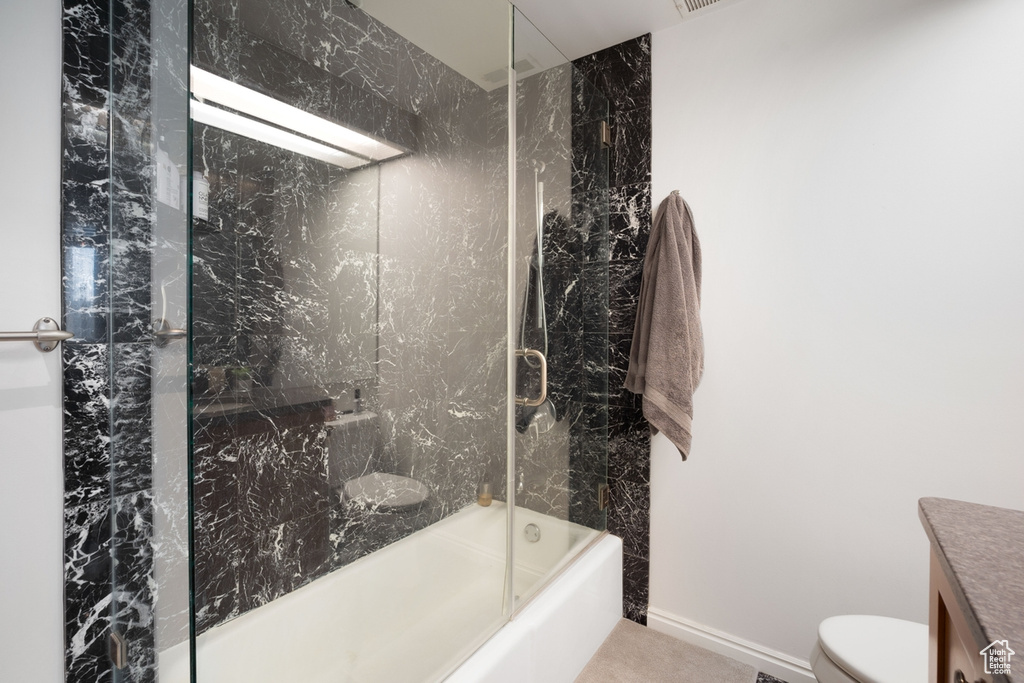 Bathroom with toilet, vanity, and combined bath / shower with glass door