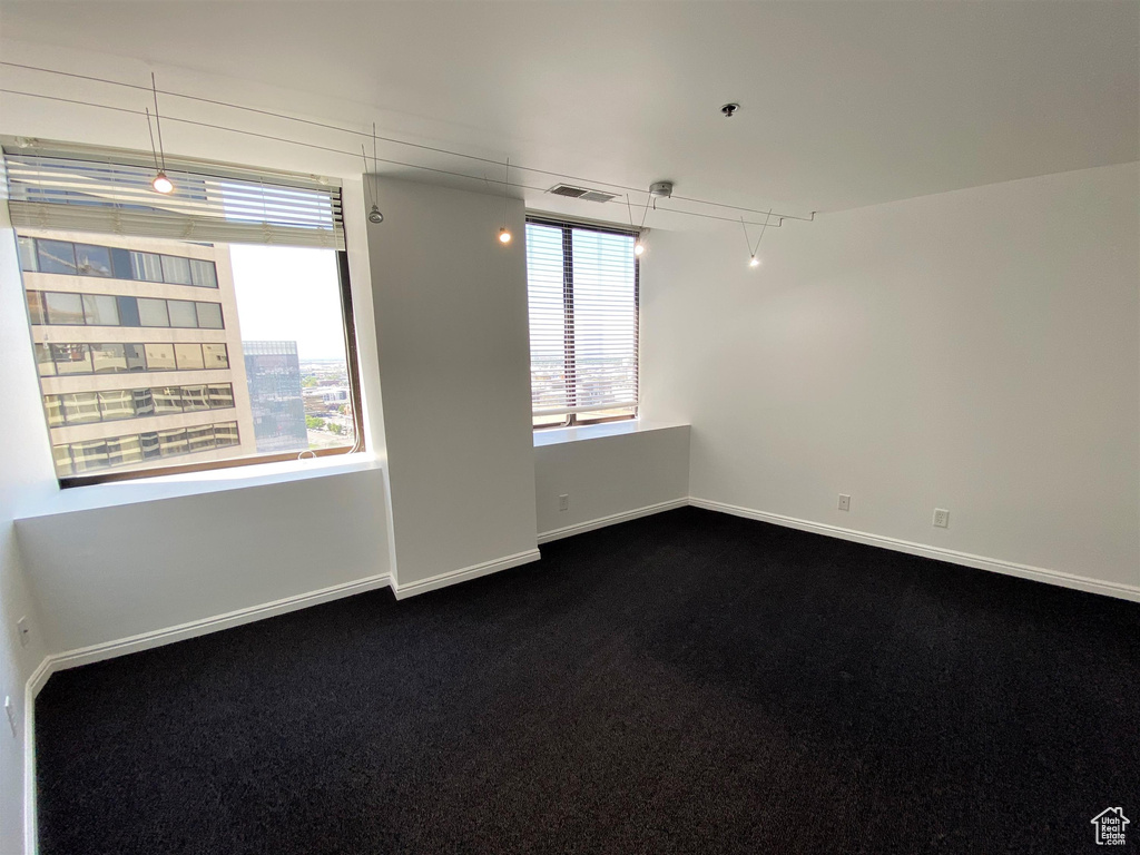 Empty room featuring baseboards and dark carpet