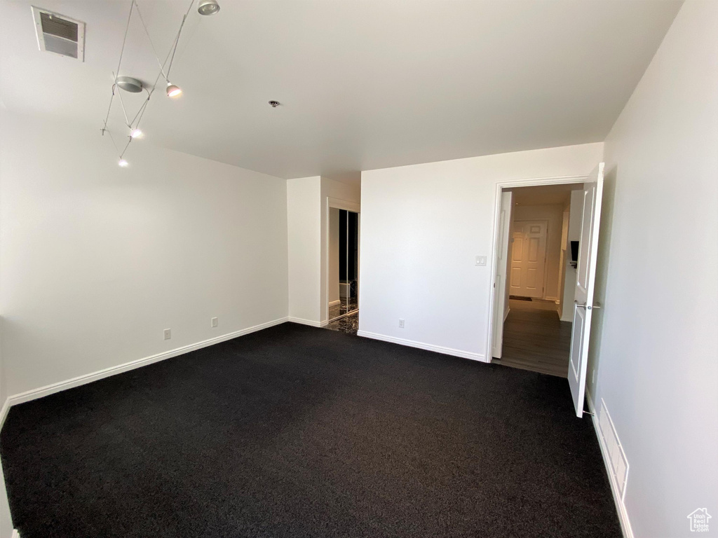 Unfurnished room with baseboards and dark carpet