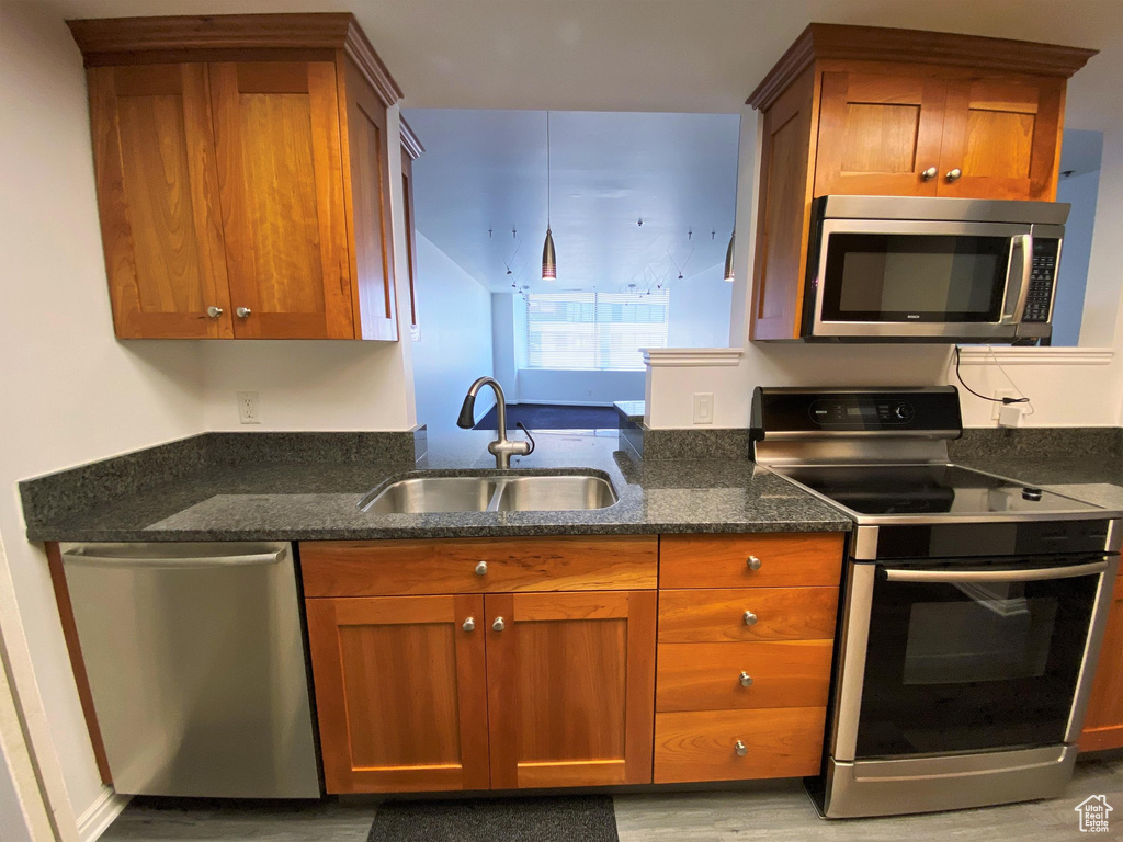 Kitchen with stainless steel appliances, a sink, and brown cabinetry