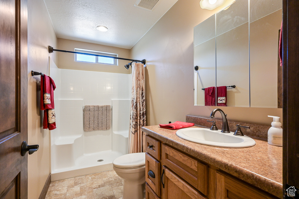 Full bath featuring a shower stall, toilet, vanity, baseboards, and a textured ceiling