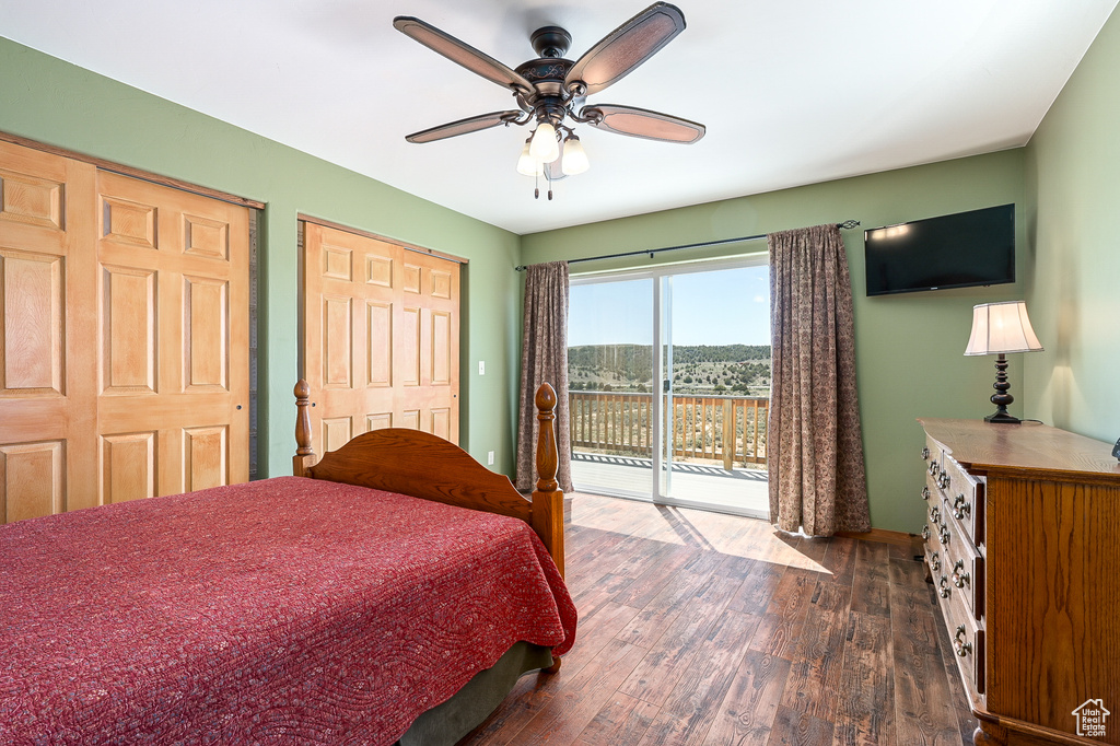 Bedroom featuring access to outside, dark wood-type flooring, ceiling fan, two closets, and baseboards