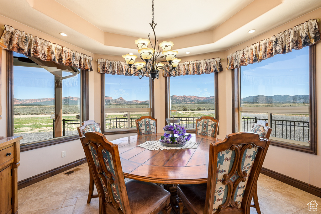 Dining room featuring a chandelier, a raised ceiling, baseboards, a mountain view, and recessed lighting