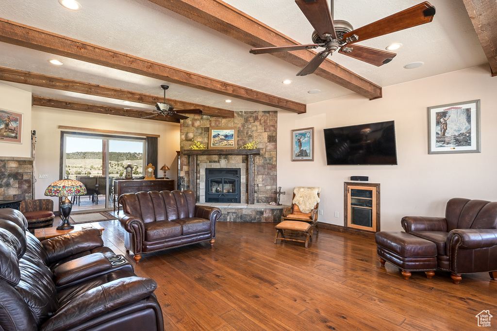 Living room featuring a stone fireplace, a ceiling fan, beam ceiling, hardwood / wood-style floors, and recessed lighting