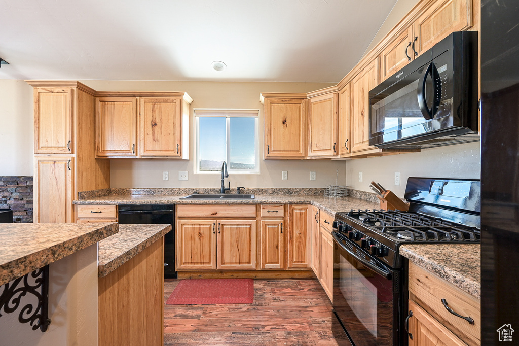 Kitchen with black appliances, a sink, dark wood-style floors, and light brown cabinetry