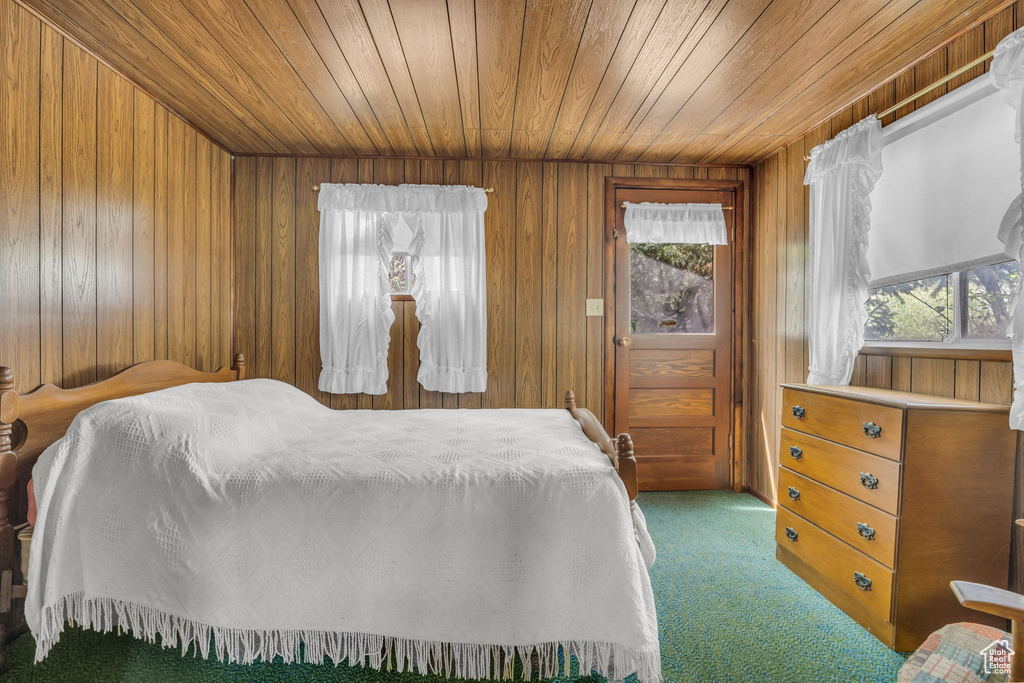 Carpeted bedroom with wood ceiling, multiple windows, and wooden walls