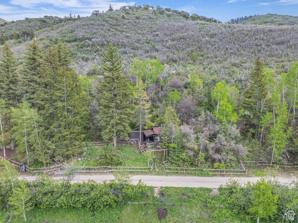 Aerial view of property and surrounding area featuring a heavily wooded area and mountains