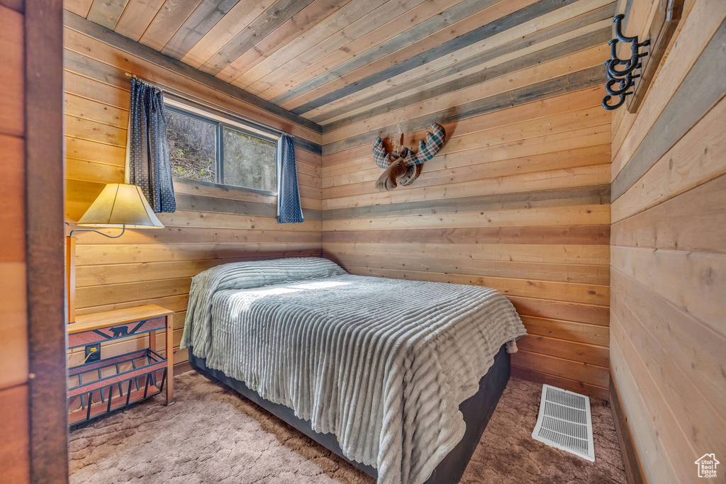 Bedroom featuring wood walls, carpet, and wooden ceiling