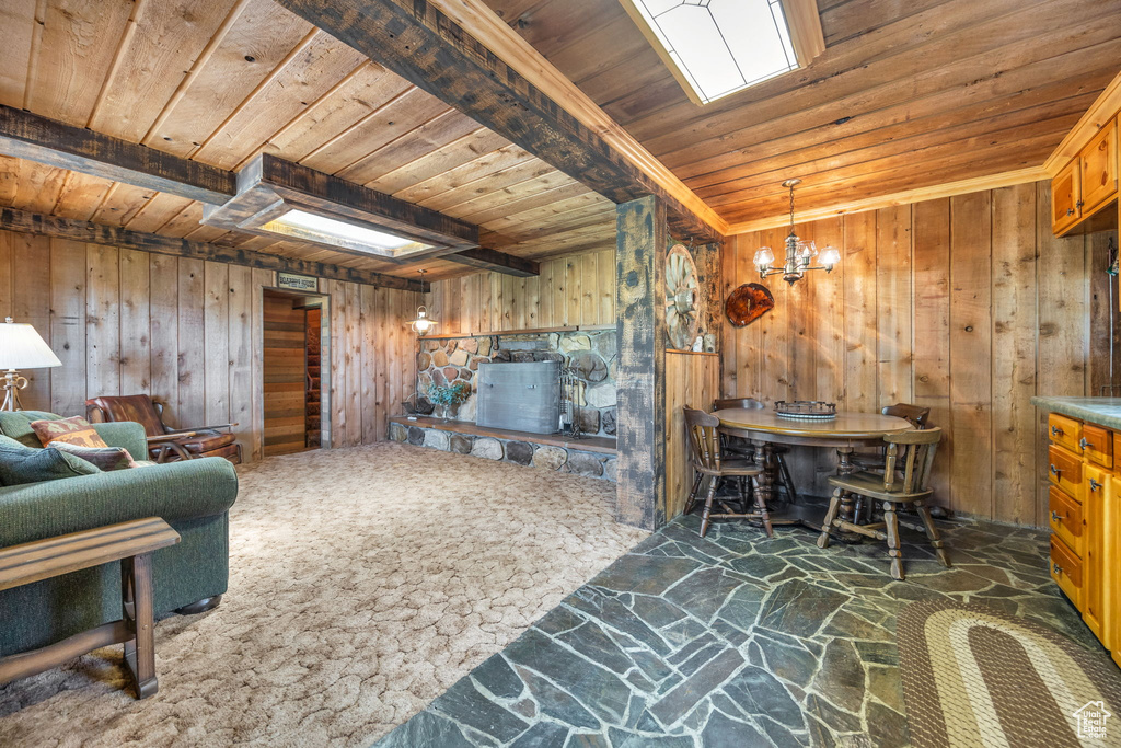 Living room with wood ceiling, stone flooring, wooden walls, and a chandelier