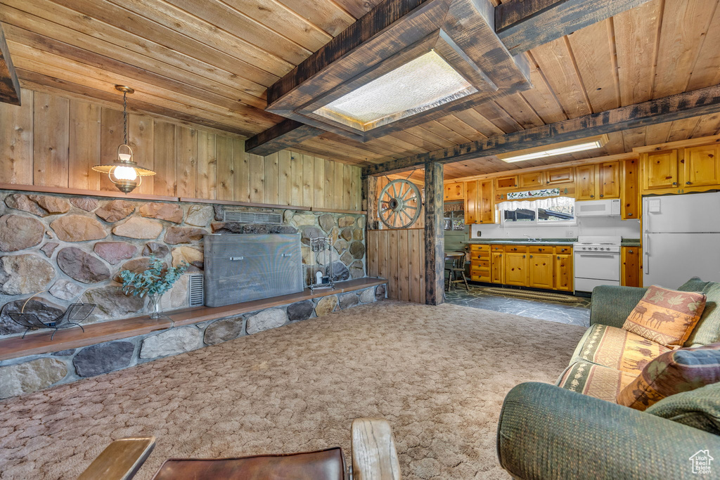 Living room with wooden ceiling, wooden walls, a skylight, and beam ceiling