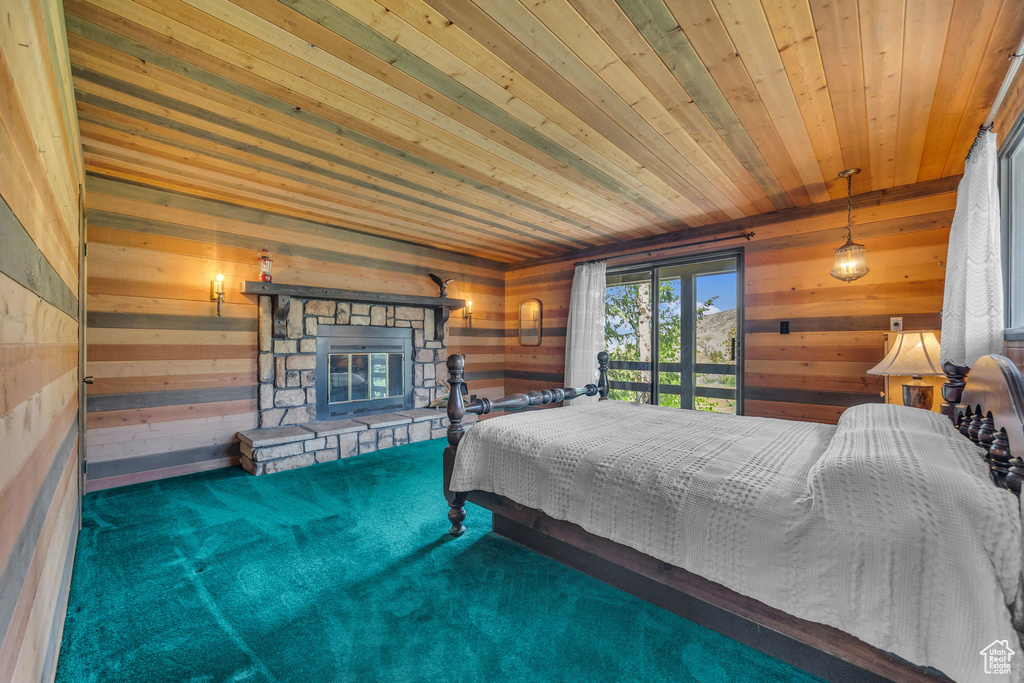 Bedroom featuring wooden walls, a stone fireplace, carpet floors, wood ceiling, and access to exterior