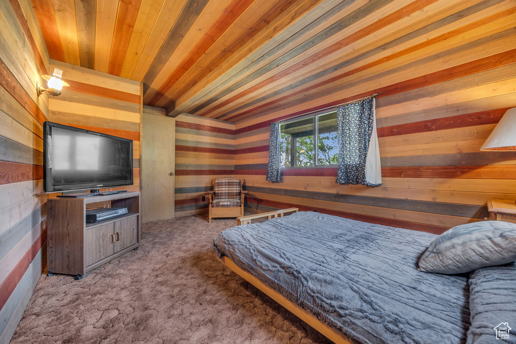 Carpeted bedroom with wood walls and wooden ceiling