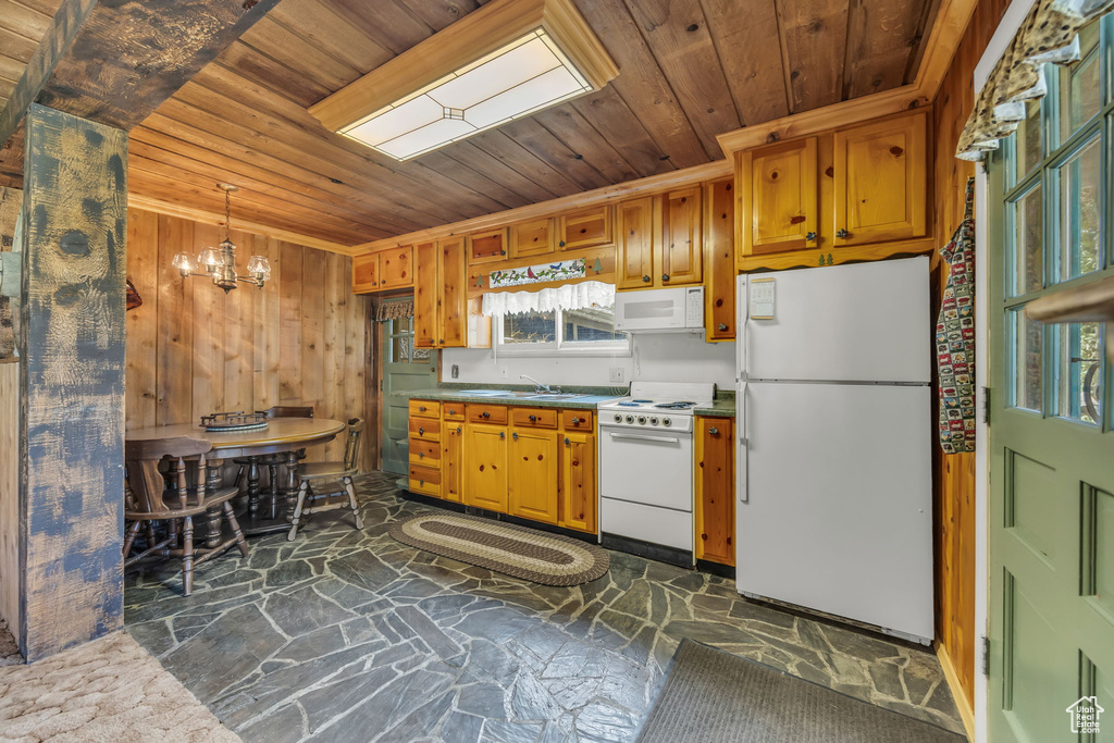 Kitchen with white appliances, stone floors, wood ceiling, a chandelier, and a sink