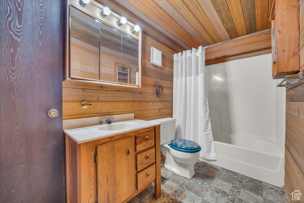 Full bath featuring wood walls, wooden ceiling, toilet, shower / tub combo with curtain, and vanity