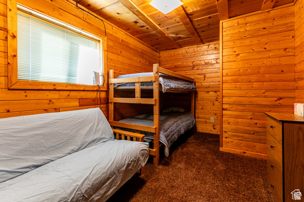 Carpeted bedroom with wood ceiling and wooden walls