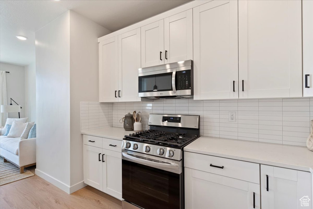 Kitchen with stainless steel appliances, light wood finished floors, white cabinetry, light countertops, and recessed lighting