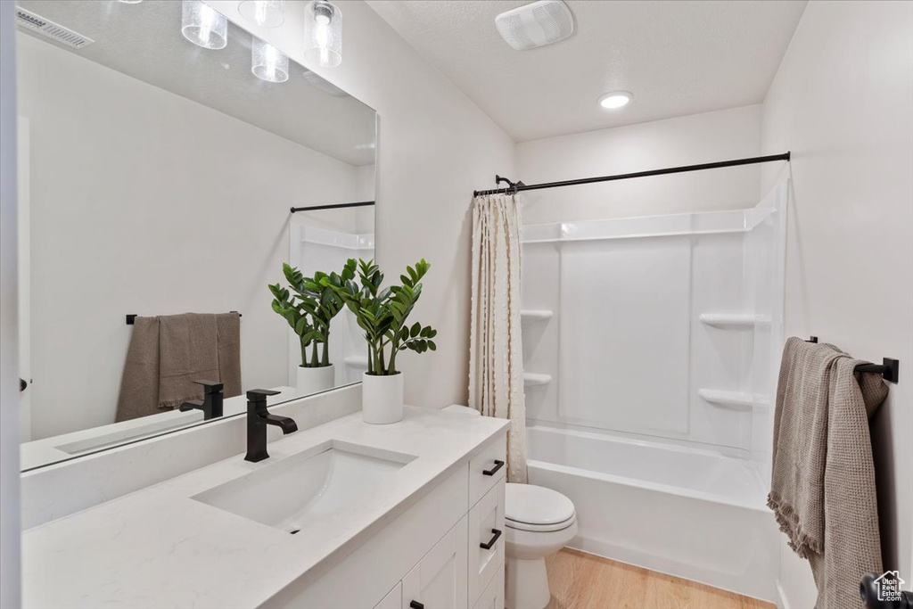 Full bathroom with vanity, shower / tub combo, wood finished floors, and recessed lighting