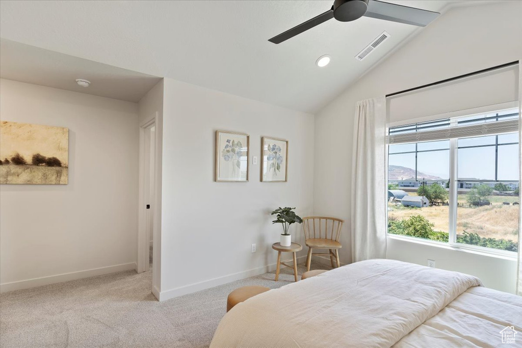Carpeted bedroom featuring vaulted ceiling and a ceiling fan