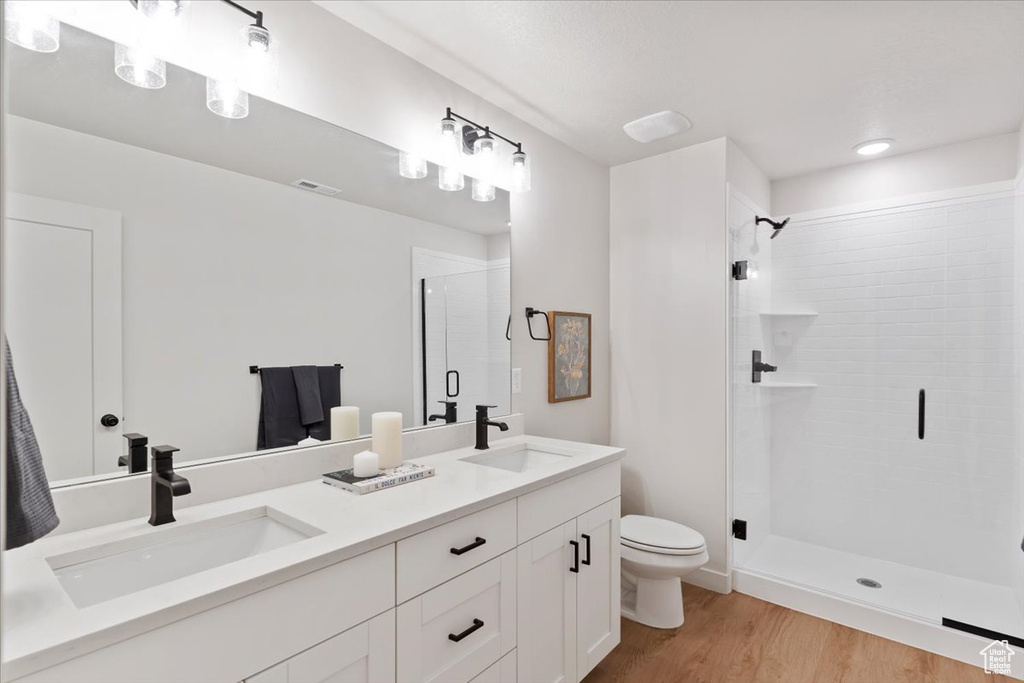 Bathroom with a stall shower, double vanity, and wood finished floors