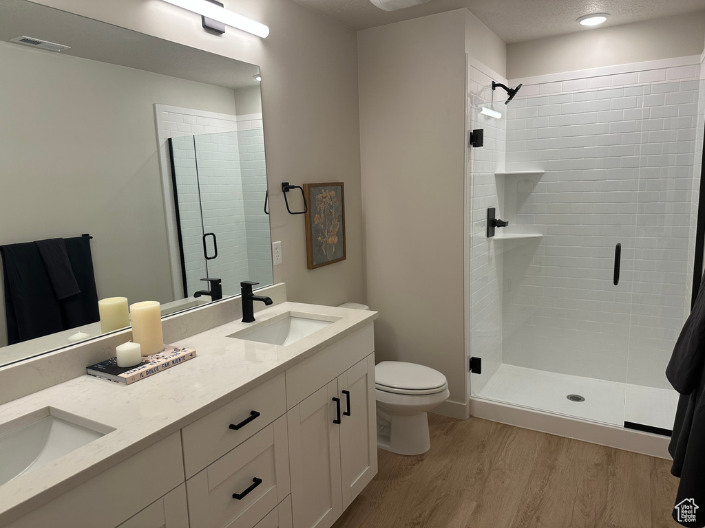 Full bath with toilet, wood finished floors, a stall shower, and double vanity