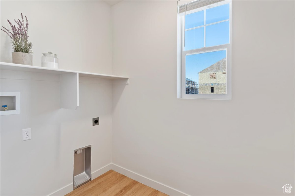 Washroom with hookup for an electric dryer, light wood-style flooring, and hookup for a washing machine