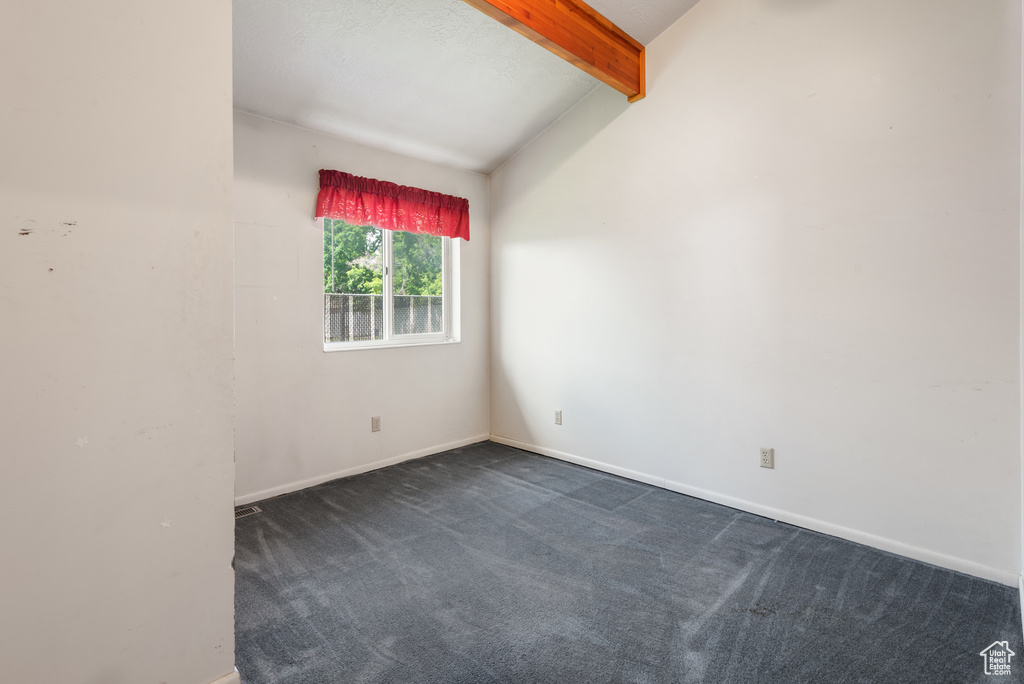 Empty room featuring dark carpet and baseboards