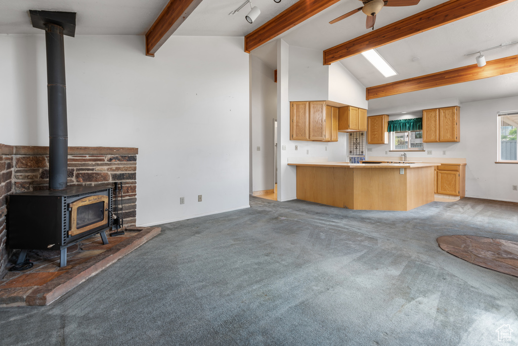 Kitchen featuring a wood stove, track lighting, light carpet, and a peninsula