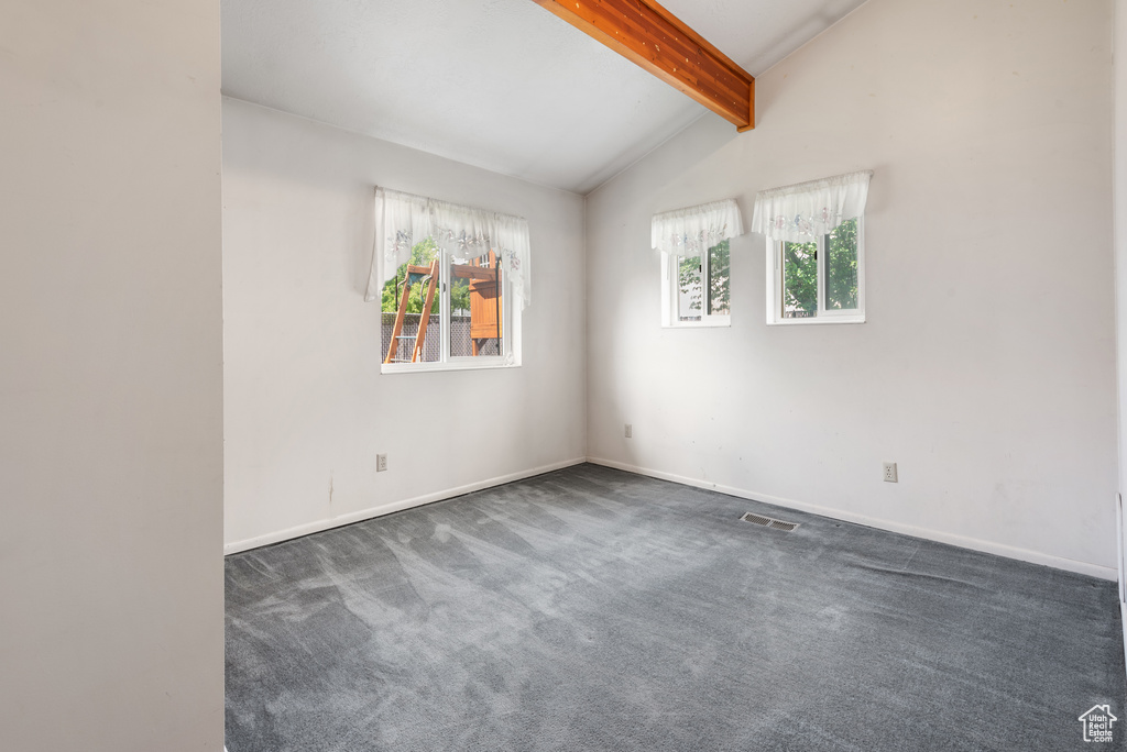 Empty room featuring healthy amount of natural light, dark carpet, and baseboards