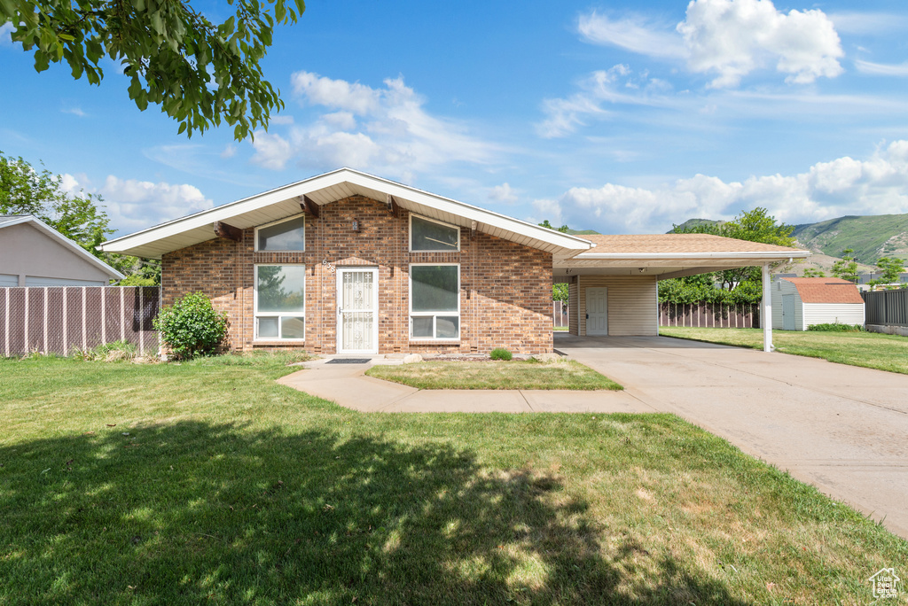 Mid-century home with brick siding, concrete driveway, an attached carport, and a mountain view