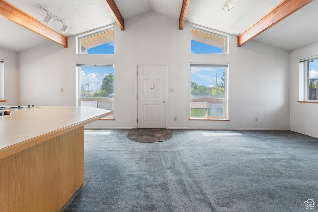 Carpeted foyer entrance featuring beam ceiling, track lighting, high vaulted ceiling, and baseboards