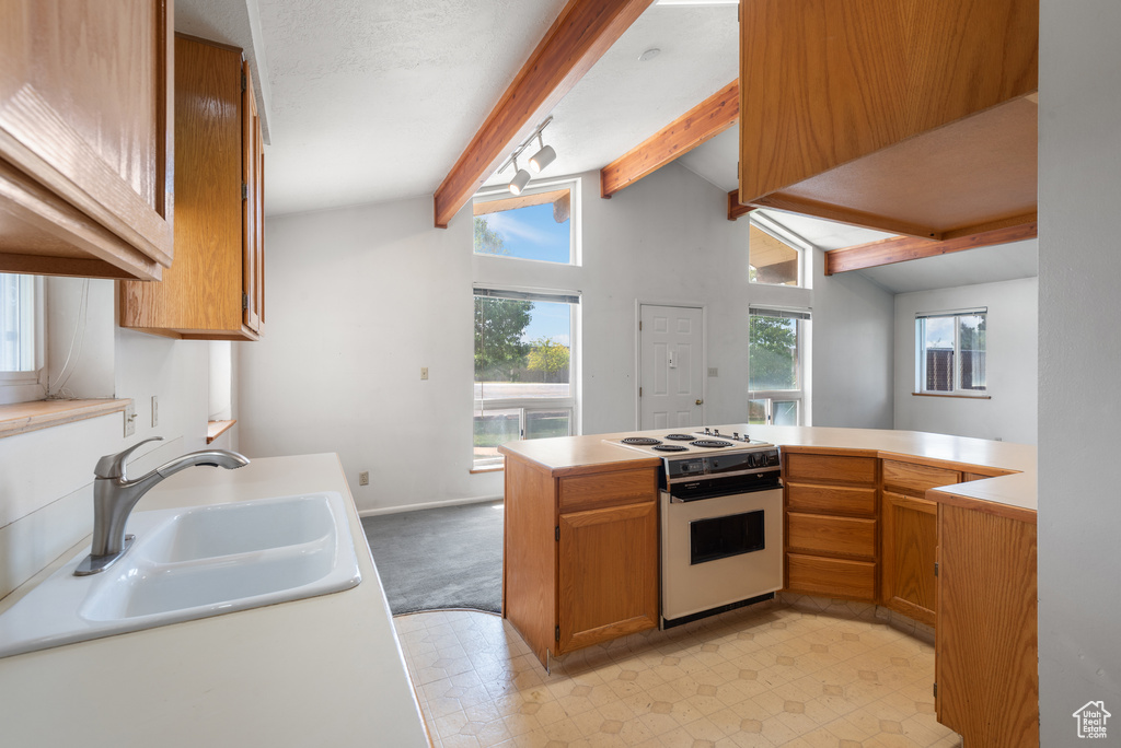 Kitchen with white stove, a sink, healthy amount of natural light, and light countertops