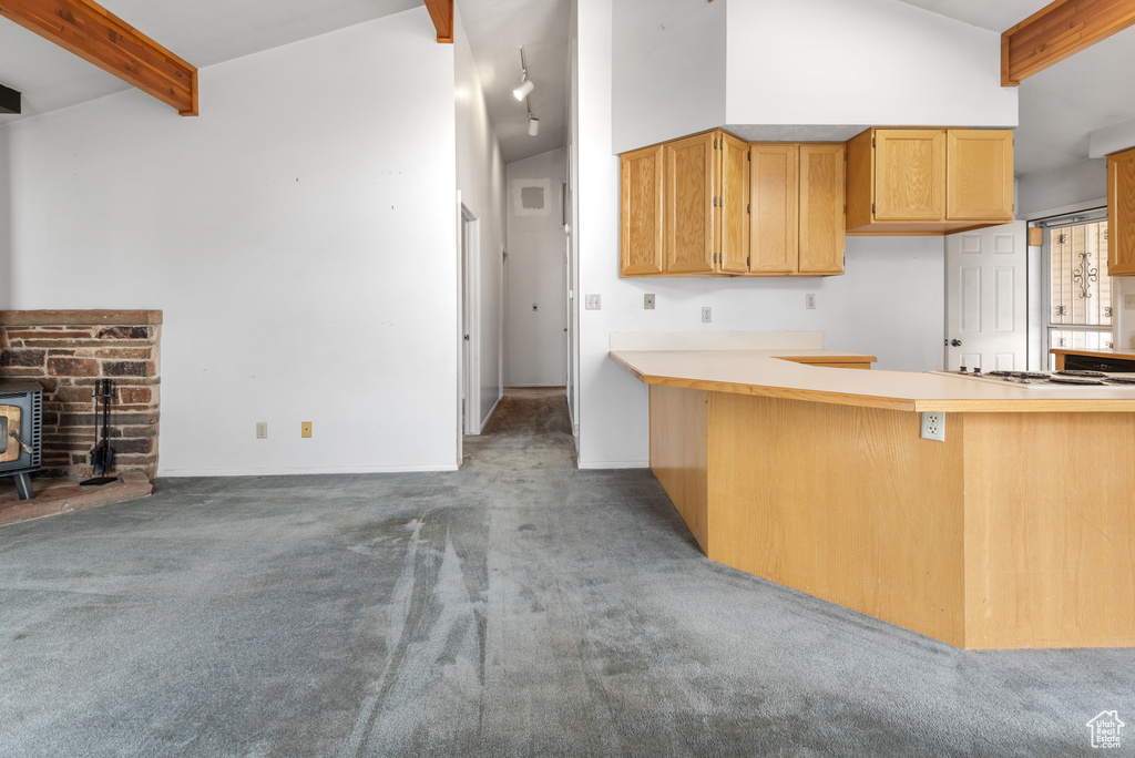 Kitchen with carpet floors, a wood stove, light countertops, white cooktop, and a peninsula