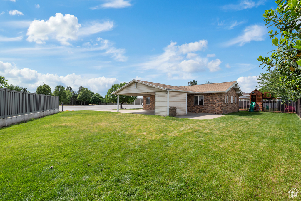 View of yard with a playground, an attached carport, and concrete driveway