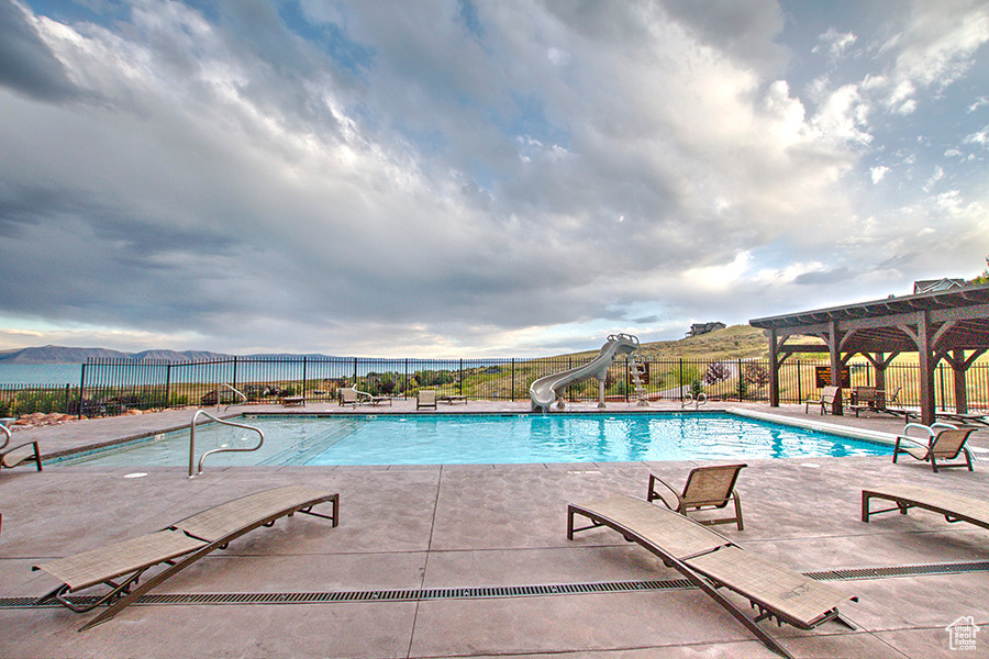 Community pool with a water slide, fence, and a pergola