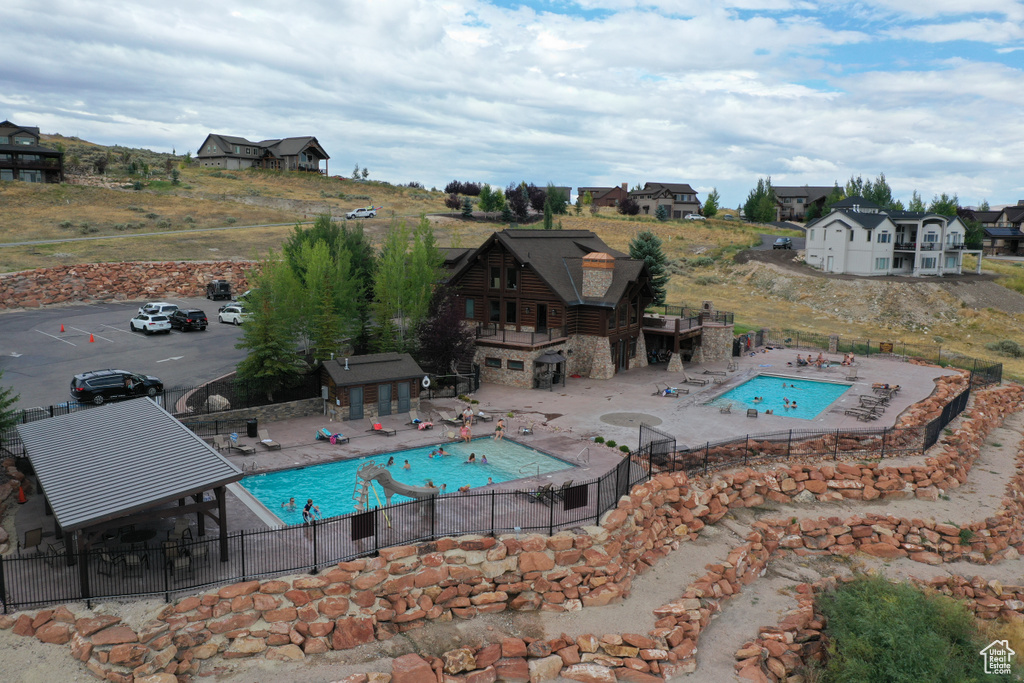 Community pool with fence, a jacuzzi, a patio area, and an outbuilding