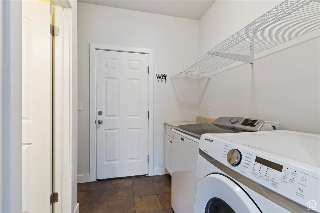 Clothes washing area with separate washer and dryer, baseboards, and cabinet space