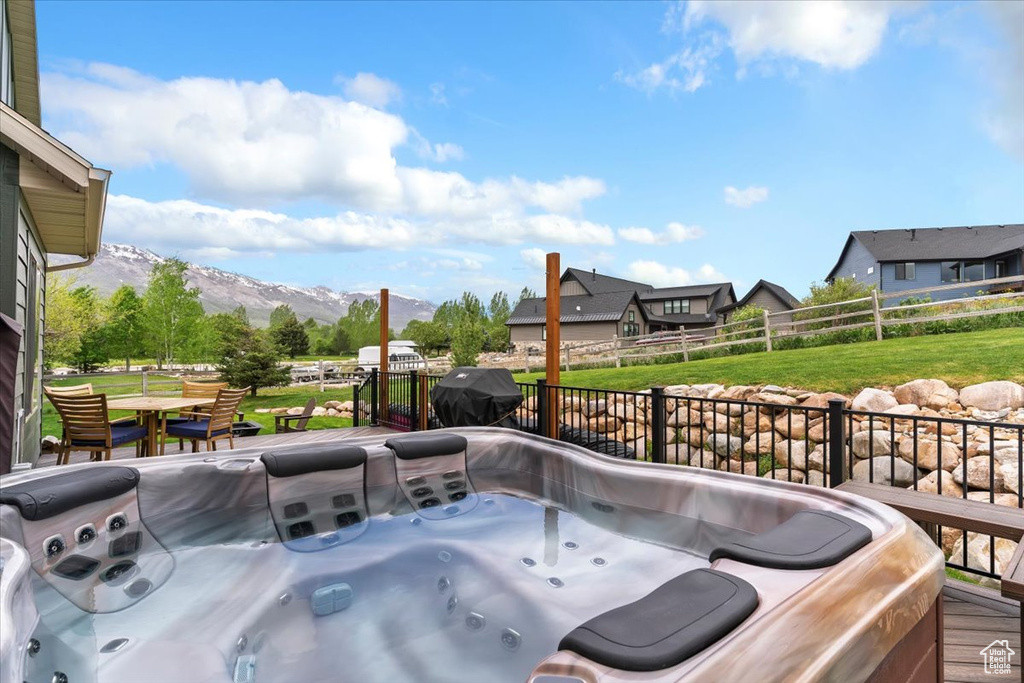 View of patio with a mountain view, a hot tub, and a grill