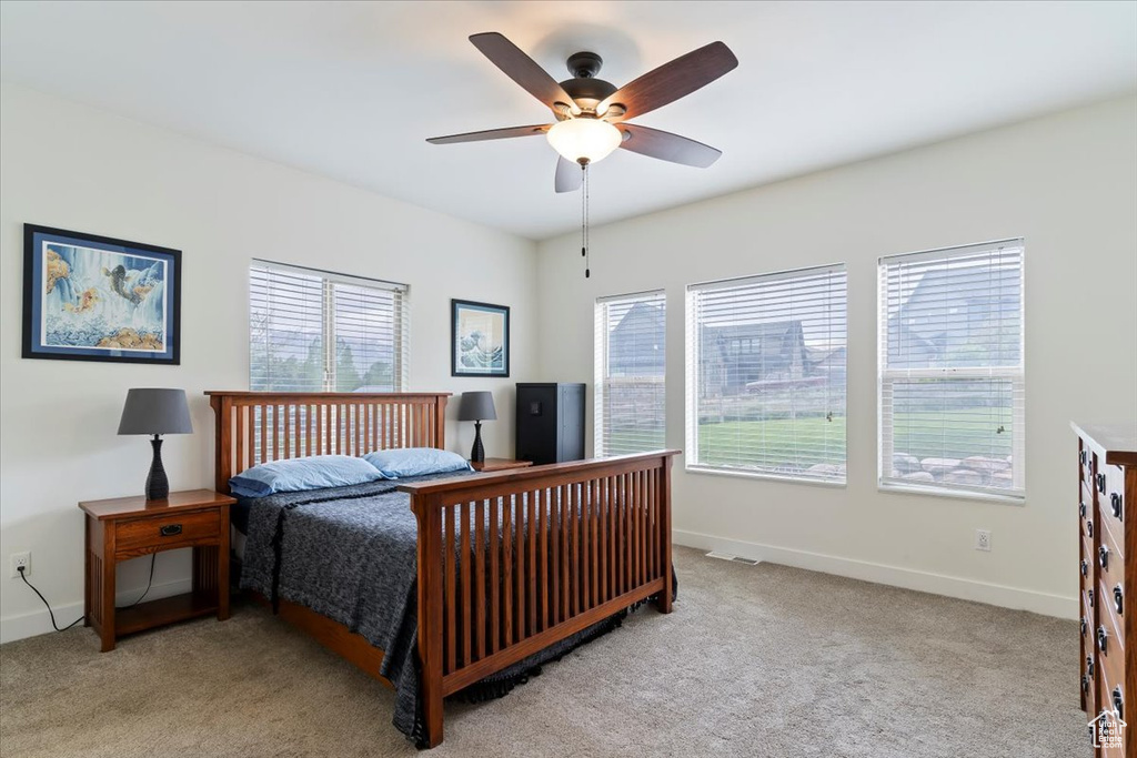 Carpeted bedroom featuring multiple windows, baseboards, and ceiling fan