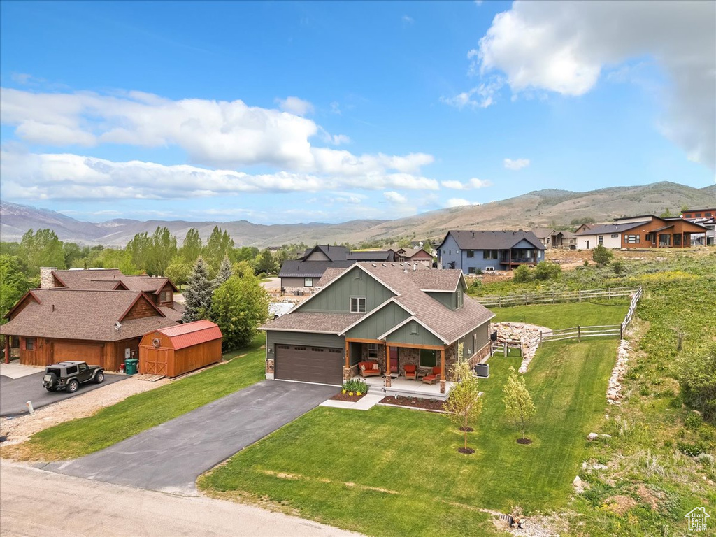 View of front of property featuring a mountain view, a porch, board and batten siding, asphalt driveway, and a garage