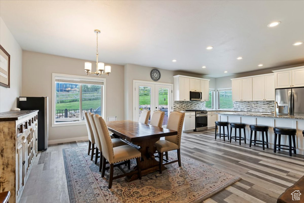 Dining area with a chandelier, light wood-style flooring, recessed lighting, baseboards, and french doors