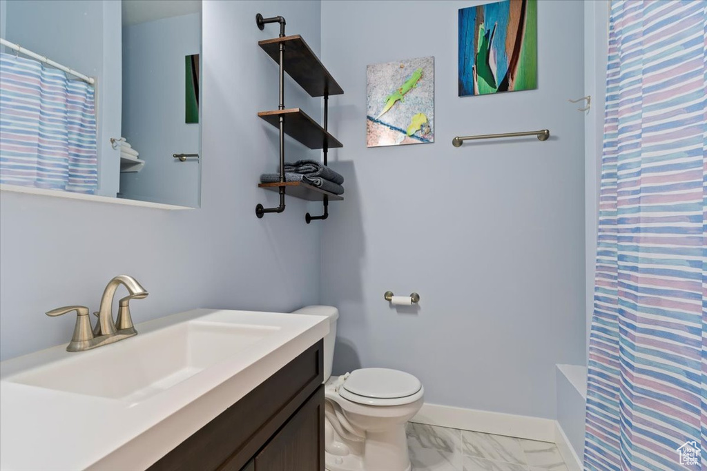 Full bath with a shower with curtain, toilet, marble look tiles, baseboards, and vanity