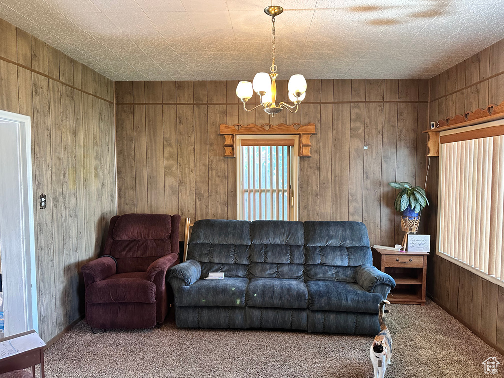 Carpeted living room with a chandelier and wood walls