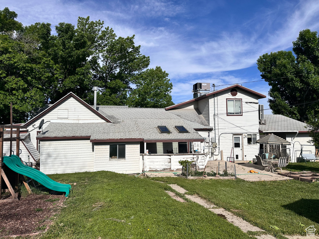 Back of house with a patio area, a playground, a yard, and roof with shingles